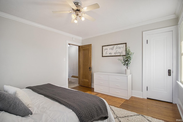 bedroom with baseboards, crown molding, ceiling fan, and wood finished floors