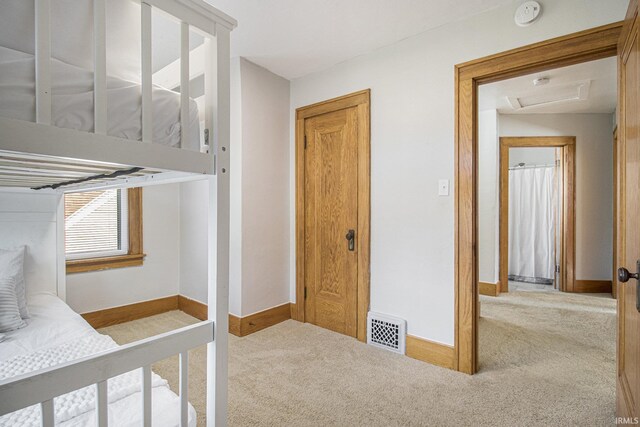 carpeted bedroom featuring visible vents, baseboards, and attic access