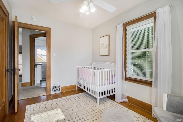 bedroom with visible vents, multiple windows, baseboards, and wood finished floors