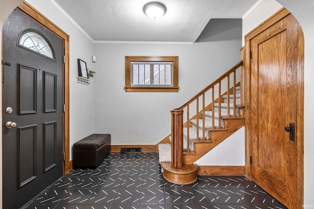 entryway featuring baseboards, arched walkways, ornamental molding, and stairs