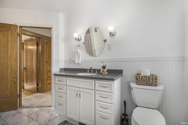 bathroom with wainscoting, vanity, toilet, and marble finish floor