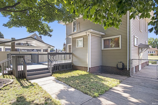 view of side of home with a lawn, a wooden deck, and fence