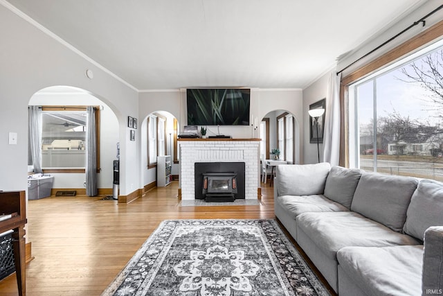 living area with baseboards, arched walkways, wood finished floors, and crown molding