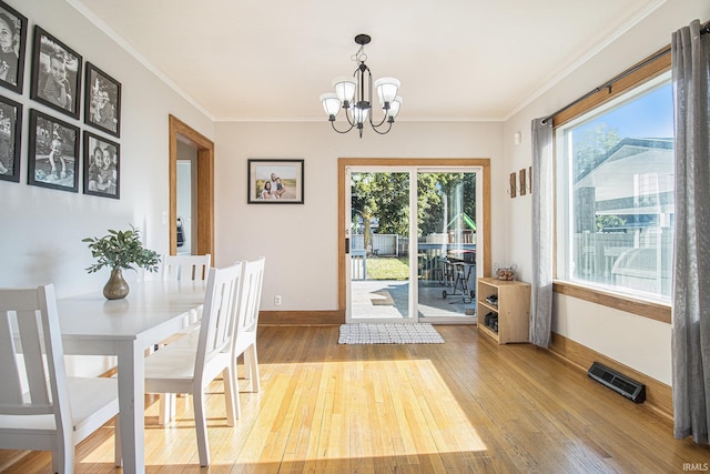 dining space with an inviting chandelier, visible vents, wood-type flooring, and ornamental molding