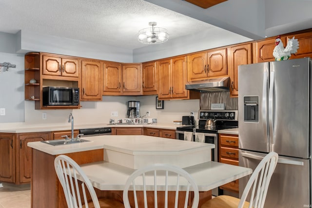 kitchen with under cabinet range hood, stainless steel appliances, and brown cabinetry