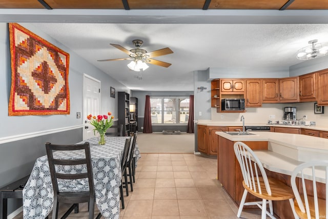 kitchen with open shelves, stainless steel microwave, light tile patterned flooring, brown cabinetry, and light countertops