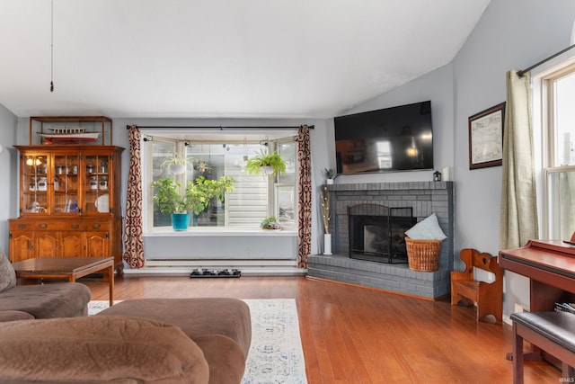 living room featuring wood finished floors, a fireplace, a wealth of natural light, and vaulted ceiling