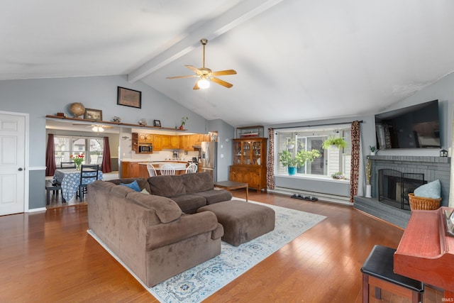 living room with lofted ceiling with beams, plenty of natural light, a brick fireplace, and wood finished floors