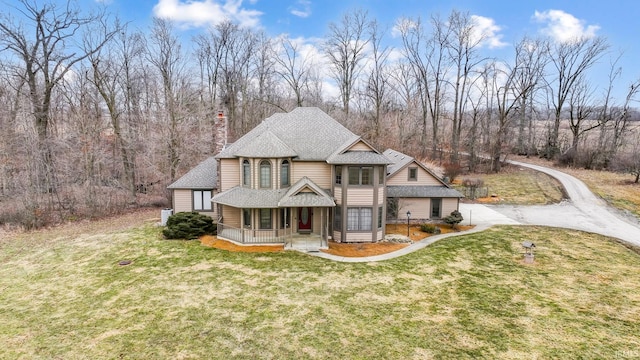 view of front of home featuring a porch, a chimney, roof with shingles, and a front lawn