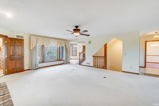 unfurnished living room featuring arched walkways, visible vents, stairs, and carpet