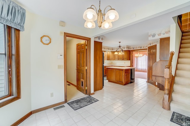 kitchen with visible vents, a kitchen island, a chandelier, light countertops, and brown cabinets