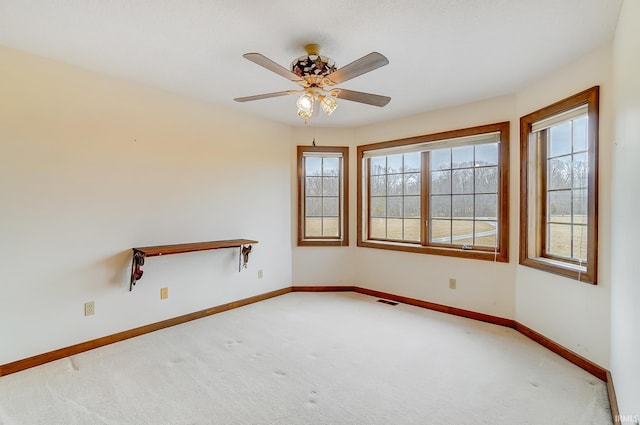 carpeted empty room with visible vents, baseboards, and ceiling fan