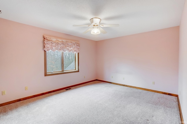 carpeted spare room featuring visible vents, baseboards, and a ceiling fan