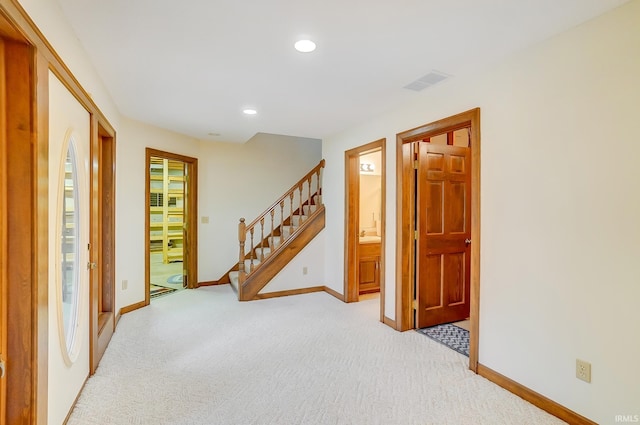 empty room featuring visible vents, recessed lighting, baseboards, light colored carpet, and stairs