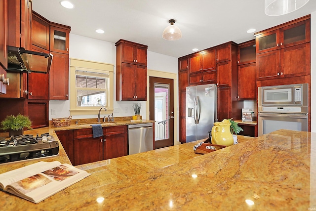 kitchen with ventilation hood, light stone counters, a sink, stainless steel appliances, and dark brown cabinets