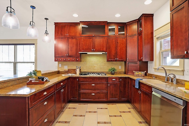 kitchen with a sink, appliances with stainless steel finishes, a peninsula, and reddish brown cabinets