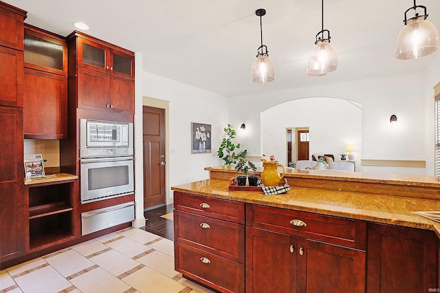 kitchen with a warming drawer, pendant lighting, light stone counters, appliances with stainless steel finishes, and dark brown cabinets