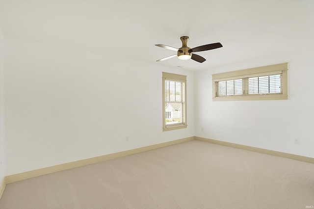 empty room featuring light colored carpet, baseboards, and ceiling fan