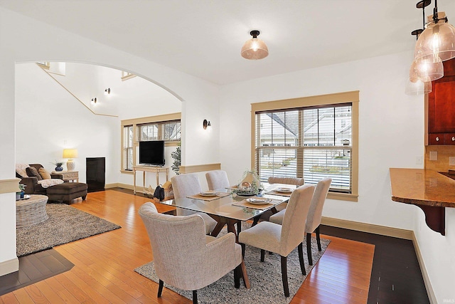 dining area with arched walkways, baseboards, and hardwood / wood-style floors