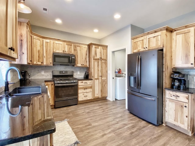 kitchen featuring refrigerator with ice dispenser, light brown cabinets, a sink, washer / clothes dryer, and gas stove