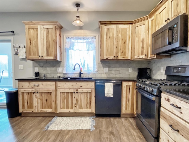 kitchen featuring dishwashing machine, a sink, light brown cabinetry, dark countertops, and stainless steel gas stove