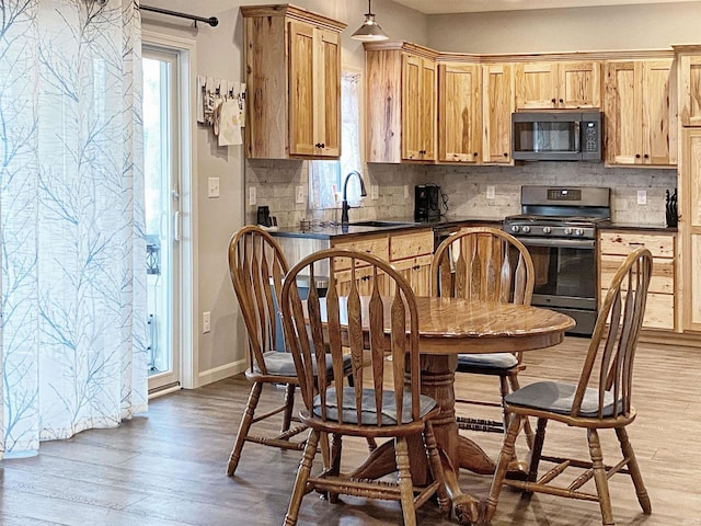 kitchen featuring light wood-type flooring, stainless steel range with gas cooktop, and dark countertops