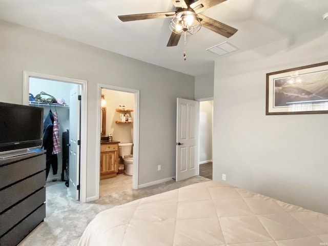 bedroom featuring a spacious closet, visible vents, connected bathroom, light carpet, and a closet