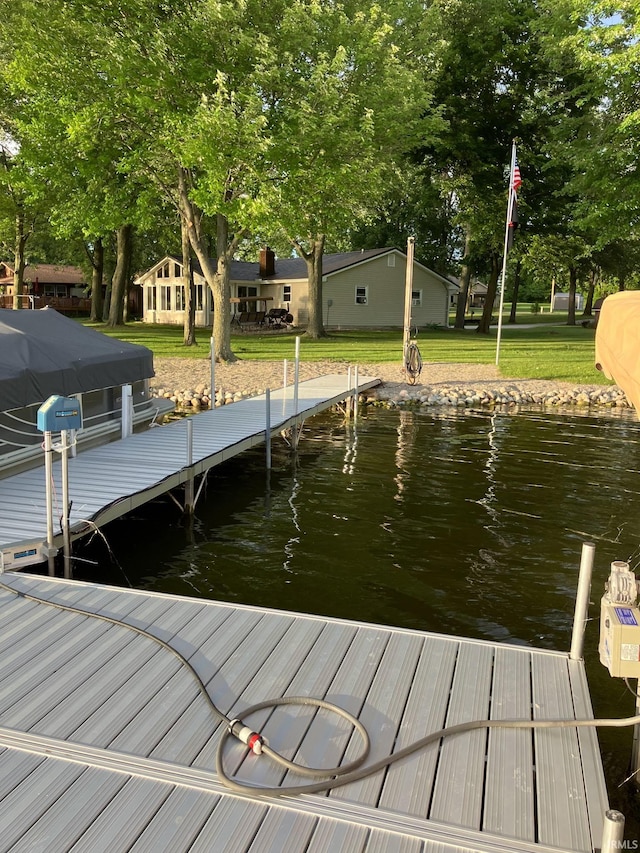 view of dock with a lawn and a water view