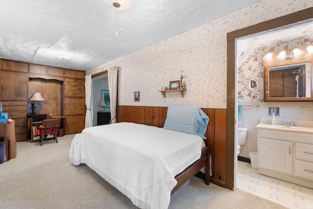 bedroom with wallpapered walls, a sink, and wainscoting