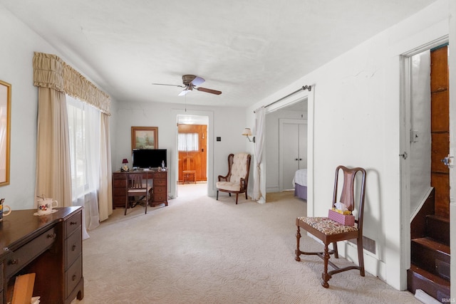 living area featuring light colored carpet and ceiling fan