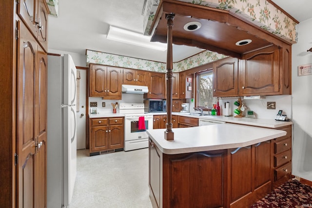 kitchen with white appliances, light floors, light countertops, under cabinet range hood, and brown cabinets