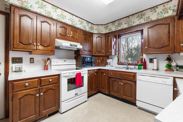 kitchen featuring white appliances, light floors, wallpapered walls, light countertops, and under cabinet range hood