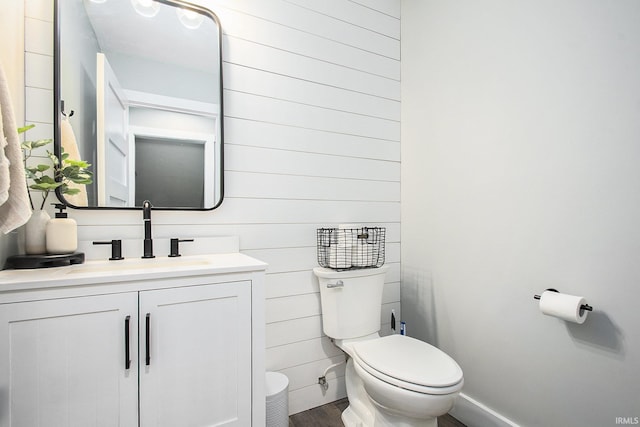 half bath featuring toilet, wood finished floors, and vanity