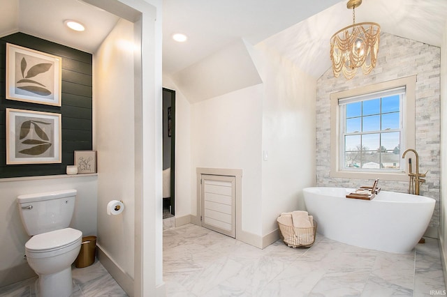 full bath featuring toilet, marble finish floor, baseboards, a soaking tub, and vaulted ceiling