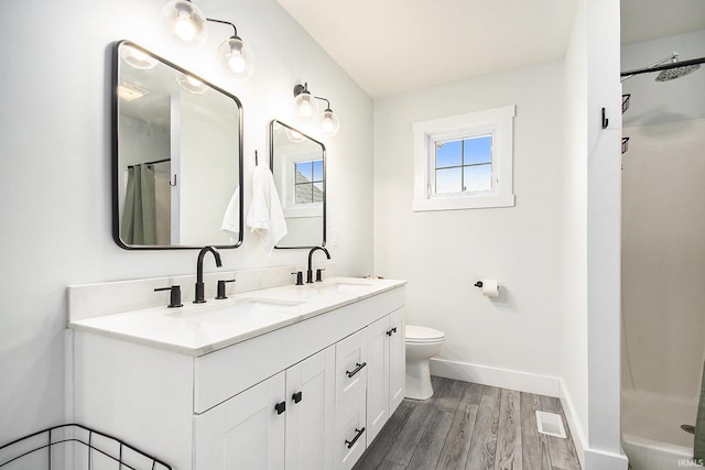 bathroom with a sink, visible vents, toilet, and wood finished floors