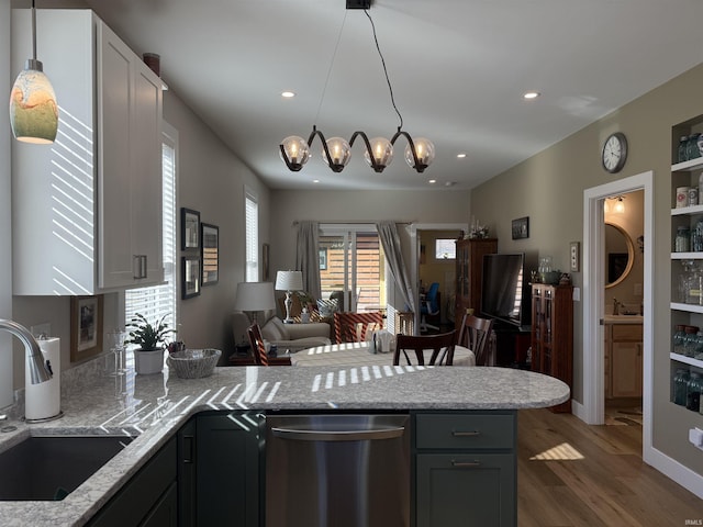 kitchen featuring a peninsula, a sink, dishwasher, open floor plan, and a chandelier