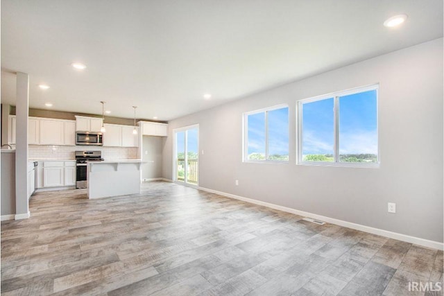 unfurnished living room with recessed lighting, light wood-style floors, and baseboards