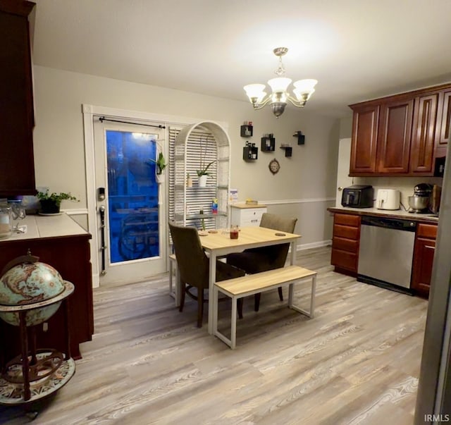 kitchen featuring light wood finished floors, a chandelier, dishwasher, pendant lighting, and light countertops