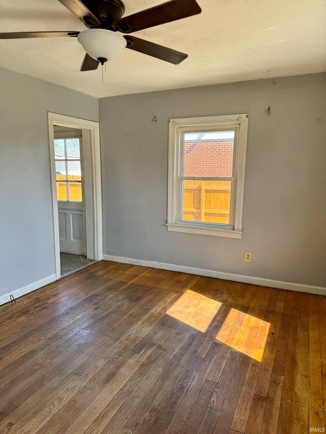 spare room featuring baseboards, wood-type flooring, a textured ceiling, and a ceiling fan