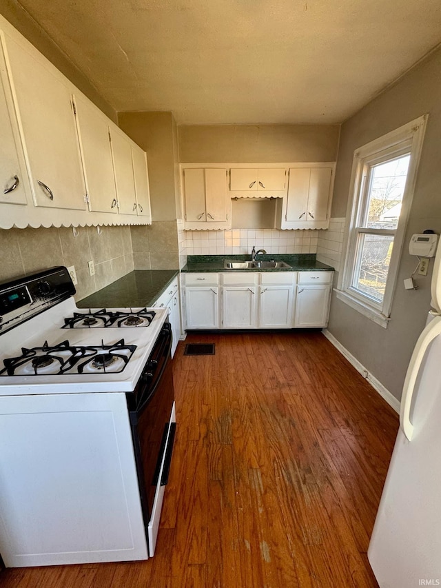 kitchen with range with gas stovetop, white cabinets, and a sink