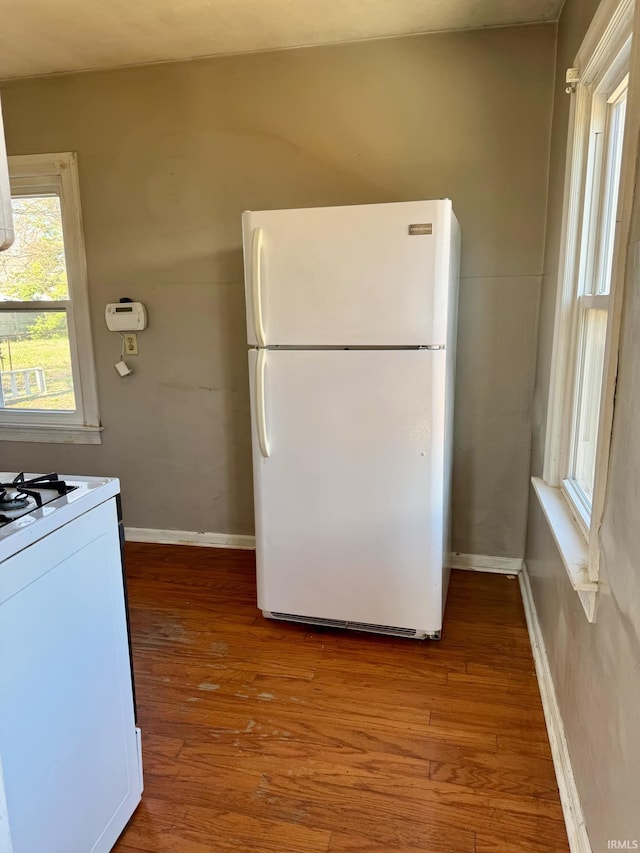 kitchen with white appliances, wood finished floors, and baseboards