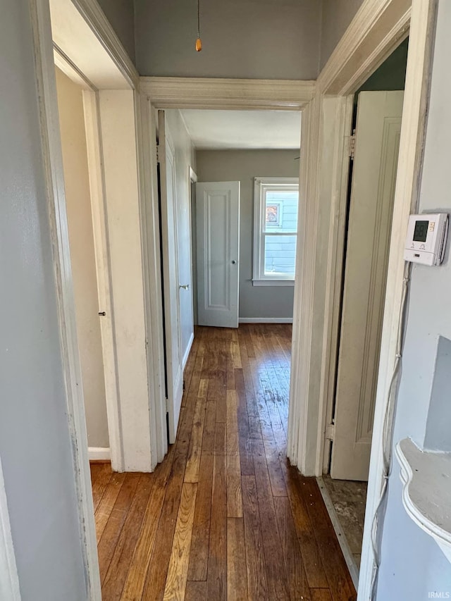 corridor featuring baseboards and dark wood finished floors