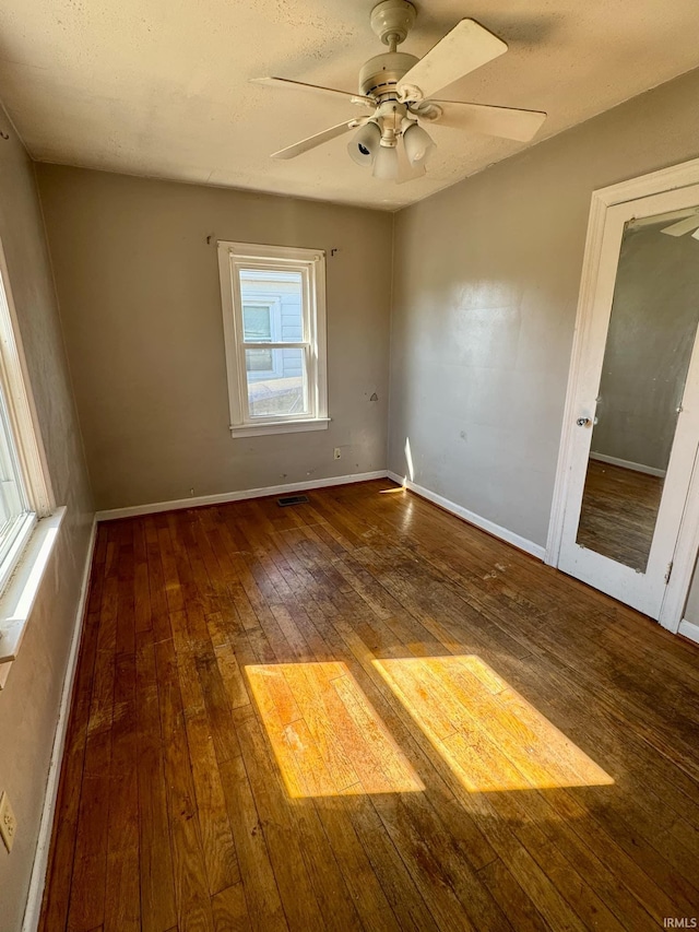 spare room featuring visible vents, ceiling fan, baseboards, and hardwood / wood-style floors