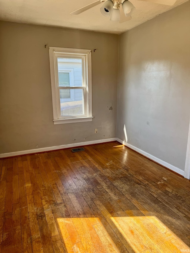 spare room featuring visible vents, wood-type flooring, baseboards, and a ceiling fan