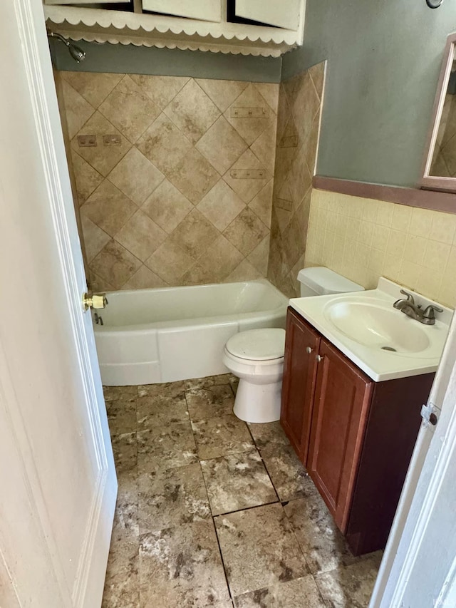 full bath featuring tile walls, a wainscoted wall, toilet, shower / bath combination, and vanity