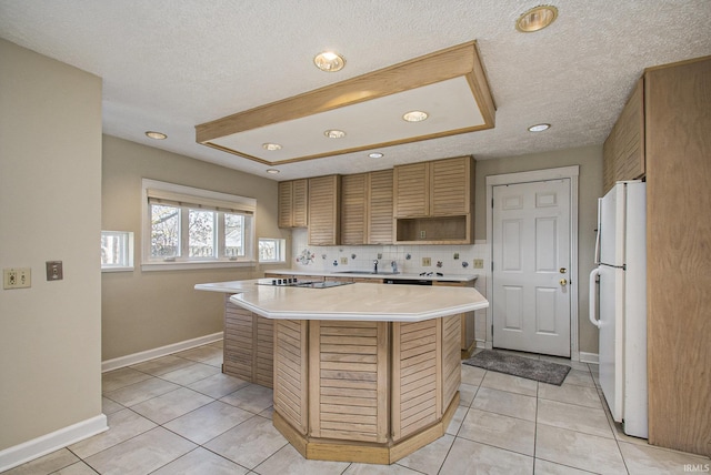 kitchen featuring a center island, baseboards, light countertops, light tile patterned floors, and freestanding refrigerator