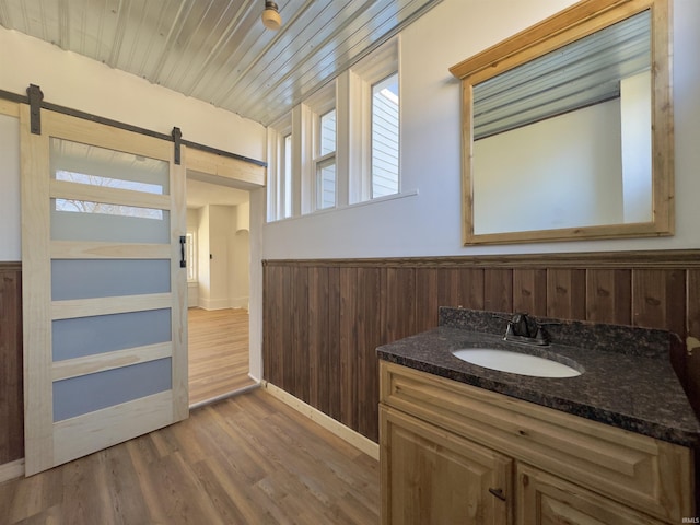 bathroom featuring vanity, wood finished floors, a wainscoted wall, wood walls, and wooden ceiling