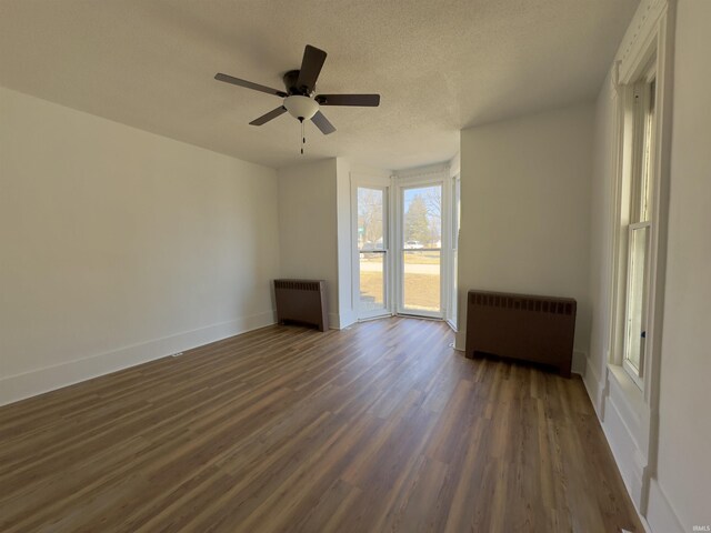 unfurnished room with radiator heating unit, baseboards, dark wood-style flooring, and a textured ceiling