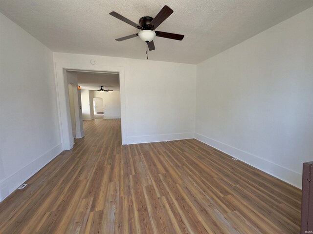 spare room featuring ceiling fan, baseboards, a textured ceiling, and wood finished floors