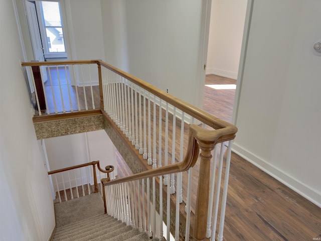 staircase featuring wood finished floors and baseboards